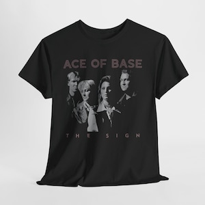 Può includere: T-shirt nera con un'immagine in scala di grigi della band Ace of Base. Il nome della band e il titolo dell'album "The Sign" sono stampati in un colore rosso-rosato sopra e sotto l'immagine della band. La maglietta è in materiale morbido.