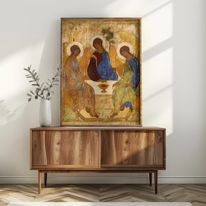 May include: A framed vertical wall art print depicting the Holy Trinity icon, featuring three figures seated around a table with a central chalice, rendered in traditional gold, blue, and earth tones with a distressed, aged texture finish.
