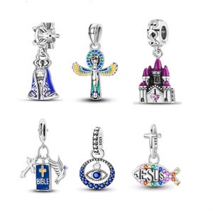 May include: Collection of silver charms with religious and symbolic designs. Includes a blue and silver Virgin Mary, an Ankh cross, a purple castle, a cross with a Bible, an eye, and a fish with the word "JESUS" in colorful gems.