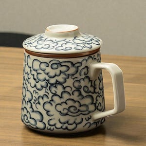Pode incluir: Caneca de cerâmica com tampa, com um padrão de nuvens azuis sobre fundo branco. A caneca tem uma alça branca e uma borda marrom na tampa. Ideal para chá ou café.