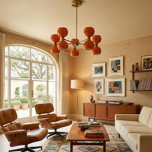 May include: A mid-century modern living room with a large arched window, two brown leather swivel chairs, and a cream-colored sofa. An orange globe chandelier hangs above a wooden coffee table and a patterned rug.