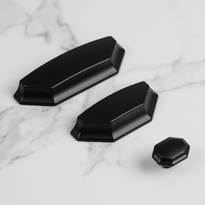 Op de afbeelding: Een set van drie keramische mokken met een gespikkelde, matte afwerking. De mokken zijn in tinten crème, lichtgrijs en donkergrijs. Elke mok heeft een eenvoudig, minimalistisch ontwerp, perfect voor koffie of thee.