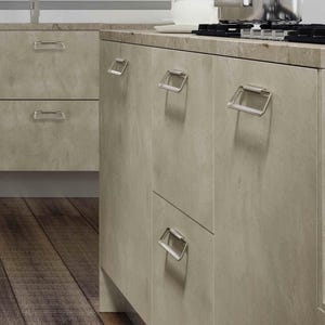 Può includere: Una cucina con mobili e cassetti grigio chiaro, con maniglie in metallo spazzolato. Il piano di lavoro è di colore marrone chiaro e una pentola in acciaio inossidabile è sul piano cottura. Il pavimento è fatto di assi di legno.