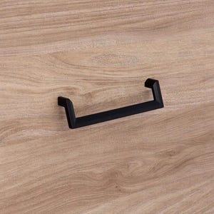 May include: A black, rectangular cabinet pull handle with a minimalist design. The handle is mounted on a light brown wooden surface, showcasing the contrast between the dark hardware and the natural wood grain. Ideal for furniture restoration or new builds.