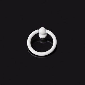 Könnte beinhalten: Ein weißer, kreisförmiger Schrankgriff mit einem Ringgriff und einem kleinen, abgerundeten Sockel. Die Hardware ist vor einem schwarzen Hintergrund platziert, was ihr schlichtes, modernes Design hervorhebt. Geeignet für Schubladen und Schränke.