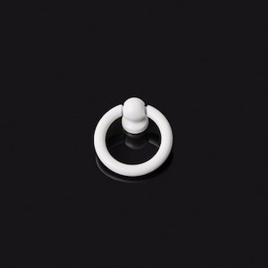 Könnte beinhalten: Ein weißer, ringförmiger Schrankgriff mit einem kreisförmigen Griff und einem kleinen, abgerundeten Sockel. Die Hardware ist vor einem schwarzen Hintergrund platziert, der ihr schlichtes, modernes Design hervorhebt. Geeignet für Schubladen und Schränke.