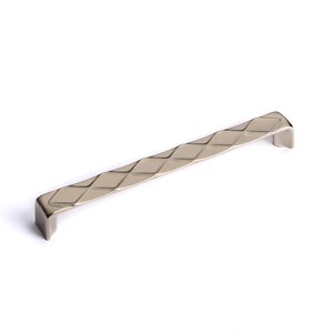 Peut inclure: Une poignée de meuble argentée avec un motif en losange. La poignée est droite avec des extrémités incurvées. La quincaillerie est probablement en métal et convient aux tiroirs ou aux portes d'armoires. Mesure environ 20 cm de long.
