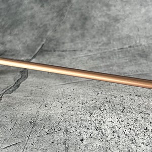 Può includere: Una maniglia per mobili color rame con una barra rettangolare e estremità curve. L'hardware è progettato per una facile installazione e aggiunge un tocco moderno a qualsiasi armadio o cassetto. La maniglia è in metallo.