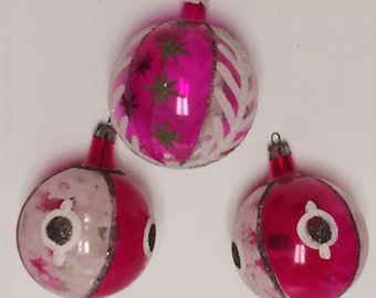 Könnte beinhalten: Drei vintage Weihnachtskugeln aus Glas mit rosa und weißer Farbe. Die Kugeln haben verschiedene Designs, darunter Sterne, Wirbel und geometrische Formen.