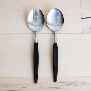 May include: A set of two silver serving utensils with black handles. The utensils are a fork and a spoon.