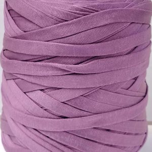 Può includere: Una bobina di nastro color lavanda, ben avvolta. Il nastro è realizzato in un materiale tessuto ed è avvolto attorno a un'anima di cartone. Il numero "44" è scritto sull'anima. Adatto per lavori di artigianato e cucito.