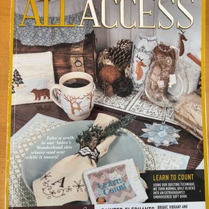 May include: The Anita Goodesign January 2018 All Access magazine cover features a collection of embroidered winter-themed crafts, including a mug cozy with a deer, a wine glass, a napkin with embroidery, and a small soft book titled Learn to Count.