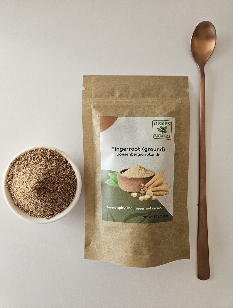 May include: A kraft paper bag of ground fingerroot with the text "Fingerroot (ground)" and "Boesenbergia rotunda". A small white bowl of ground fingerroot and a copper-coloured spoon are also present. The text reads "Sweet-spicy Thai fingerroot aroma."