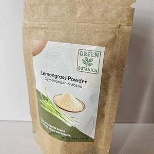 Pode incluir: Um saco de papel castanho com um r&oacute;tulo com o texto "Lemongrass Powder" e a marca "Green Botanica". O r&oacute;tulo mostra uma tigela de p&oacute;, caules de capim-lim&atilde;o e o texto "lemongrass aroma". O peso l&iacute;quido &eacute; de 50 g.