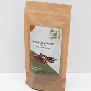 Peut inclure: Un sachet en papier brun contenant du poivre long s&eacute;ch&eacute;, &eacute;tiquet&eacute; Green Botanica, Dried Long Pepper (whole), Piper retrofractum, avec un poids net de 100 g / 3,53 oz. L'&eacute;tiquette pr&eacute;sente une illustration des poivres et du texte.