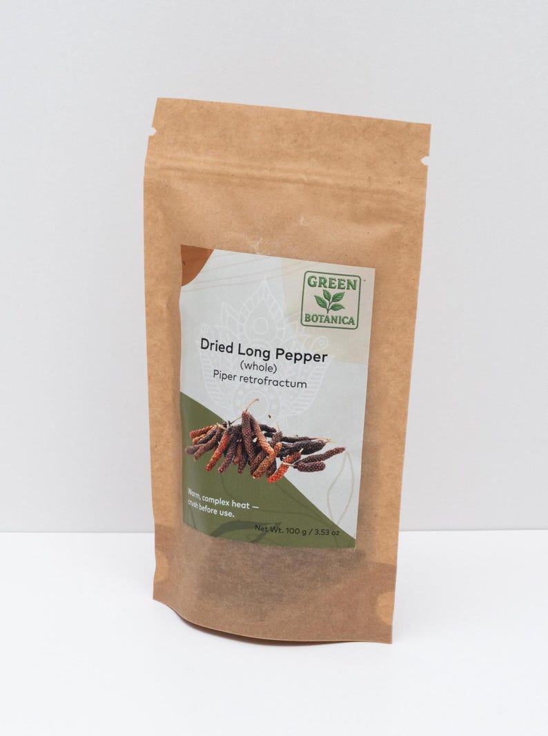 Peut inclure: Un sachet en papier brun contenant du poivre long s&eacute;ch&eacute;, &eacute;tiquet&eacute; Green Botanica, Dried Long Pepper (whole), Piper retrofractum, avec un poids net de 100 g / 3,53 oz. L'&eacute;tiquette pr&eacute;sente une illustration des poivres et du texte.