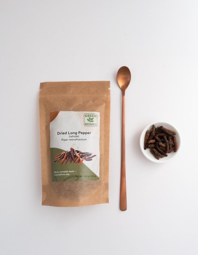 Peut inclure: Un sachet en papier brun &eacute;tiquet&eacute; Green Botanica Dried Long Pepper (whole) Piper retrofractum avec un poids net de 100 g / 3,53 oz, une longue cuill&egrave;re en m&eacute;tal cuivr&eacute; et un petit bol blanc rempli de morceaux de poivre long s&eacute;ch&eacute; brun fonc&eacute;.