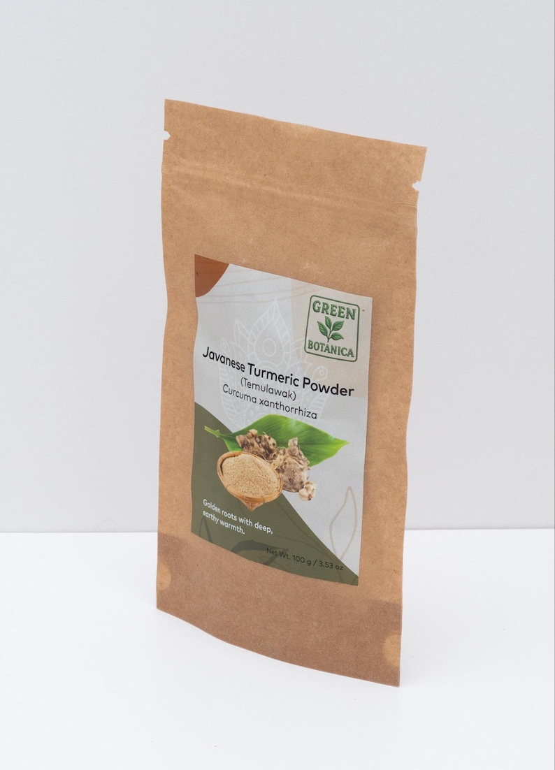 Op de afbeelding: Een bruine papieren zak met Javaans kurkumapoeder. Het etiket bevat de tekst "Javanese Turmeric Powder (Temulawak) Curcuma xanthorrhiza" met een illustratie van kurkumawortels en -bladeren. De zak bevat 100 g poeder.