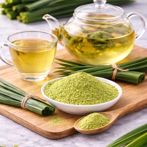 May include: A glass teapot and a glass cup filled with light green tea, a white bowl containing a mound of fine green powder, a wooden spoon with green powder, and bundles of long, slender green leaves on a wooden board.
