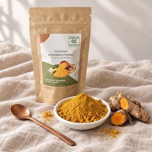 May include: A brown paper pouch labelled Green Botanica Curcuma Aromatica Powder, a white bowl filled with bright yellow turmeric powder, a copper-coloured spoon, and two raw turmeric rhizomes, one of which is sliced to reveal a vibrant orange interior.