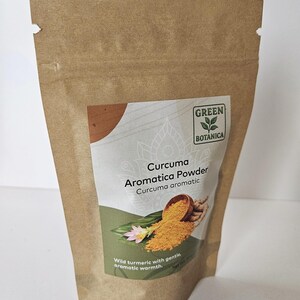May include: A brown paper bag of Curcuma Aromatica Powder. The bag has a label with the text "GREEN BOTANICA" and "Curcuma Aromatica Powder". The label also features an illustration of turmeric powder and a flower. The text "Wild turmeric with gentle, aromatic warmth" is also visible.