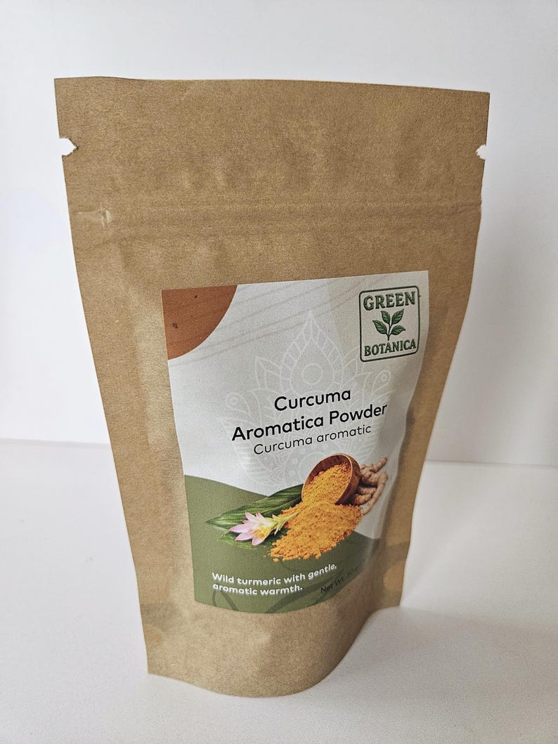 May include: A brown paper bag of Curcuma Aromatica Powder. The bag has a label with the text "GREEN BOTANICA" and "Curcuma Aromatica Powder". The label also features an illustration of turmeric powder and a flower. The text "Wild turmeric with gentle, aromatic warmth" is also visible.