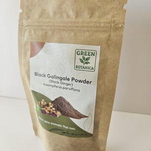 Może przedstawiać: Brązowa torebka stojąca z papieru kraftowego zawierająca sproszkowany czarny galgant. Etykieta zawiera logo Green Botanica, tekst Black Galingale Powder (Black Ginger) Kaempferia parviflora, obraz korzenia i proszku oraz napis Net Wt. 50 g.