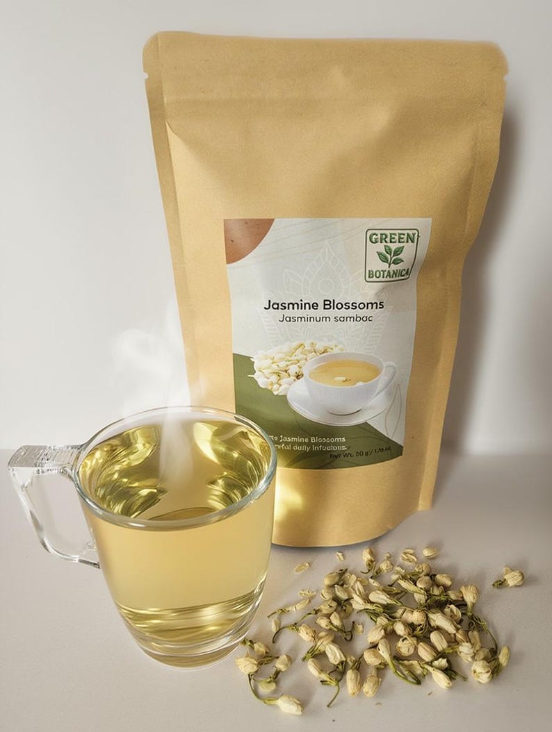 Peut inclure: Une tasse en verre remplie de th&eacute; dor&eacute;, de la vapeur s'en d&eacute;gage, &agrave; c&ocirc;t&eacute; d'un sachet en papier kraft de Fleurs de Jasmin. Le sac porte une &eacute;tiquette avec le texte "Green Botanica" et "Fleurs de Jasmin". Des fleurs de jasmin s&eacute;ch&eacute;es sont &eacute;parpill&eacute;es &agrave; proximit&eacute;.