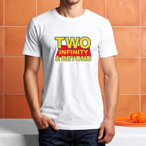 May include: White t-shirt with the text "TWO INFINITY & BEYOND" in yellow and red. The shirt is being worn by a person. The person is wearing blue jeans. Two oranges are on an orange tray.
