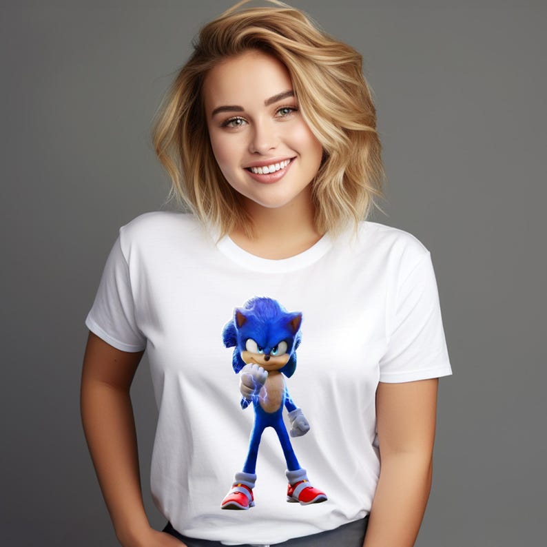 May include: White t-shirt featuring a vibrant graphic of Sonic the Hedgehog. The blue character is in a dynamic pose, with red shoes and a determined expression. The shirt is a classic crew neck style.