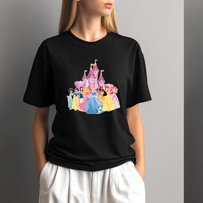 May include: Black t-shirt with a colourful graphic of a pink castle and several princesses in gowns. The princesses are in blue, yellow, pink, and green. The castle has multiple towers and flags.