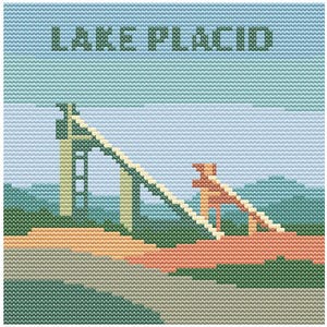 May include: A cross-stitch design featuring the text "LAKE PLACID" above a ski jump structure. The artwork uses a pixelated style with shades of green, blue, orange, and beige, evoking a vintage aesthetic. The sky is light blue.