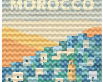May include: A cross-stitch design featuring the word "MOROCCO" above a stylized landscape. The artwork depicts a cityscape in shades of blue, green, and cream, with a yellow and orange mountain range and a light blue sky.