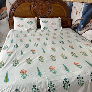May include: White bedsheet set with a floral pattern in orange, green, and blue. The set includes a fitted sheet and two pillowcases. The bed frame is made of dark wood.