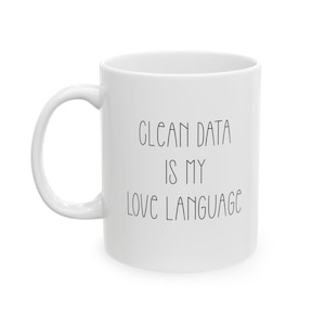 May include: White ceramic mug with a curved handle. The mug features the text "CLEAN DATA IS MY LOVE LANGUAGE" in black, handwritten-style lettering. A simple, everyday coffee mug.