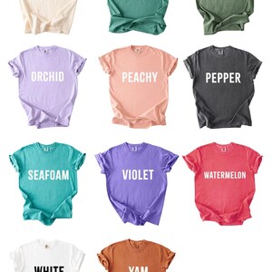 a collection of nine t-shirts in various colors and designs, arranged in a grid pattern.