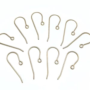 May include: Ten gold-toned earring hooks, also known as ear wires, are scattered on a white background. The hooks are made of metal and have a simple, classic design.