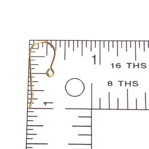 May include: Gold-toned earring hook with a loop at the top and a small hook at the bottom. The hook is measured against a ruler, showing it is just over 1 inch long.
