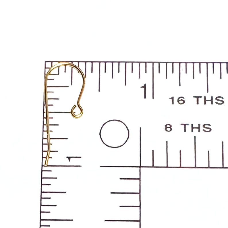 May include: Gold-toned earring hook with a loop at the top and a small hook at the bottom. The hook is measured against a ruler, showing it is just over 1 inch long.