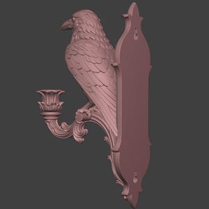 May include: A mauve-colored wall-mounted candle holder featuring a sculpted raven perched on a curved, ornate branch. The piece includes a decorative candle cup and a vertical backplate with two keyhole slots for mounting to a flat surface.