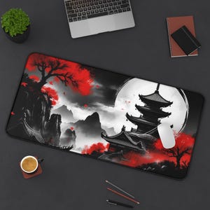 Puede incluir: Alfombrilla de ratón rectangular negra con un diseño de paisaje japonés. La obra de arte incluye una pagoda, árboles rojos y una luna llena sobre un fondo negro y gris. Un ratón blanco está en el lado derecho.