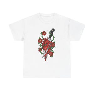 May include: White t-shirt featuring a graphic design of a red heart pierced by a knife, surrounded by red roses and green vines. The design has a tattoo-inspired aesthetic.