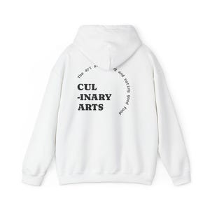 以下が含まれることがあります： 黒い太字で「CULINARY ARTS」の文字が入った白いパーカー。テキストの上には「The art of」があり、右上には「ing and eating good food」が曲線状の黒いフォントで書かれています。スウェットシャツはゆったりとしたフィット感です。