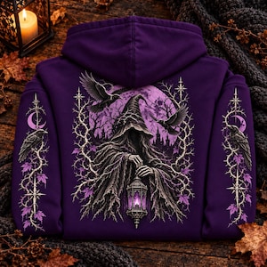 May include: A deep purple hooded sweatshirt featuring a graphic print of a cloaked figure in a pointed hat holding a glowing lantern. The design includes ravens, thorny vines, purple maple leaves, and a full moon. Similar raven and vine motifs appear on both sleeves.