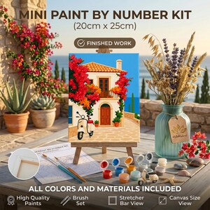 May include: A mini paint by number kit measuring 20cm x 25cm, featuring a canvas on a wooden easel depicting a Mediterranean house with a scooter, accompanied by small paint pots, brushes, and a printed guide on a table surface.