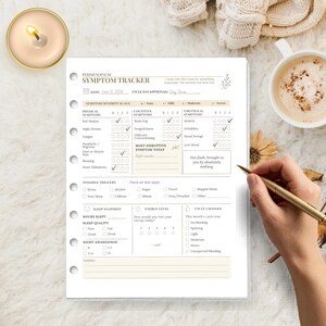 May include: A white paper perimenopause symptom tracker sheet with six binder holes on the left side. The form includes sections for physical, cognitive, and emotional symptoms, triggers, sleep, energy levels, and cycle changes with printed text.