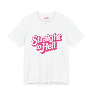 Könnte beinhalten: Weißes T-Shirt mit dem Schriftzug "Straight to Hell" in rosa, im Retro-Stil. Der Text ist mittig auf der Vorderseite des Shirts platziert. Das Shirt hat kurze Ärmel und einen Rundhalsausschnitt.