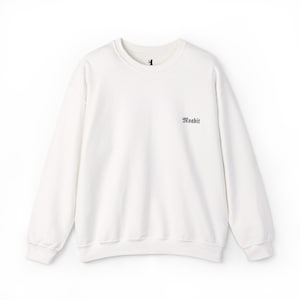 Puede incluir: Sudadera blanca de cuello redondo y manga larga. La palabra "Woabit" está impresa en una fuente oscura en el lado derecho del pecho. Un pequeño gráfico negro está en la parte superior central de la sudadera.