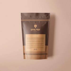 May include: A brown coffee bag with the text "SAFARI PRIDE COFFEE" and "OUR STORY" printed on it. The bag has a decorative pattern at the top and bottom. The background is a light brown color.