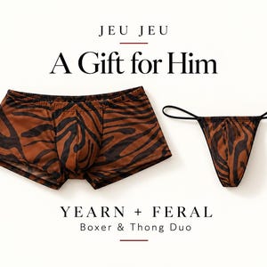Puede incluir: Unos calzoncillos tipo bóxer y un tanga con un patrón de rayas de tigre en marrón y negro. El texto JEU JEU A Gift for Him y YEARN + FERAL Boxer & Thong Duo está impreso sobre y bajo las prendas en una fuente serif negra.